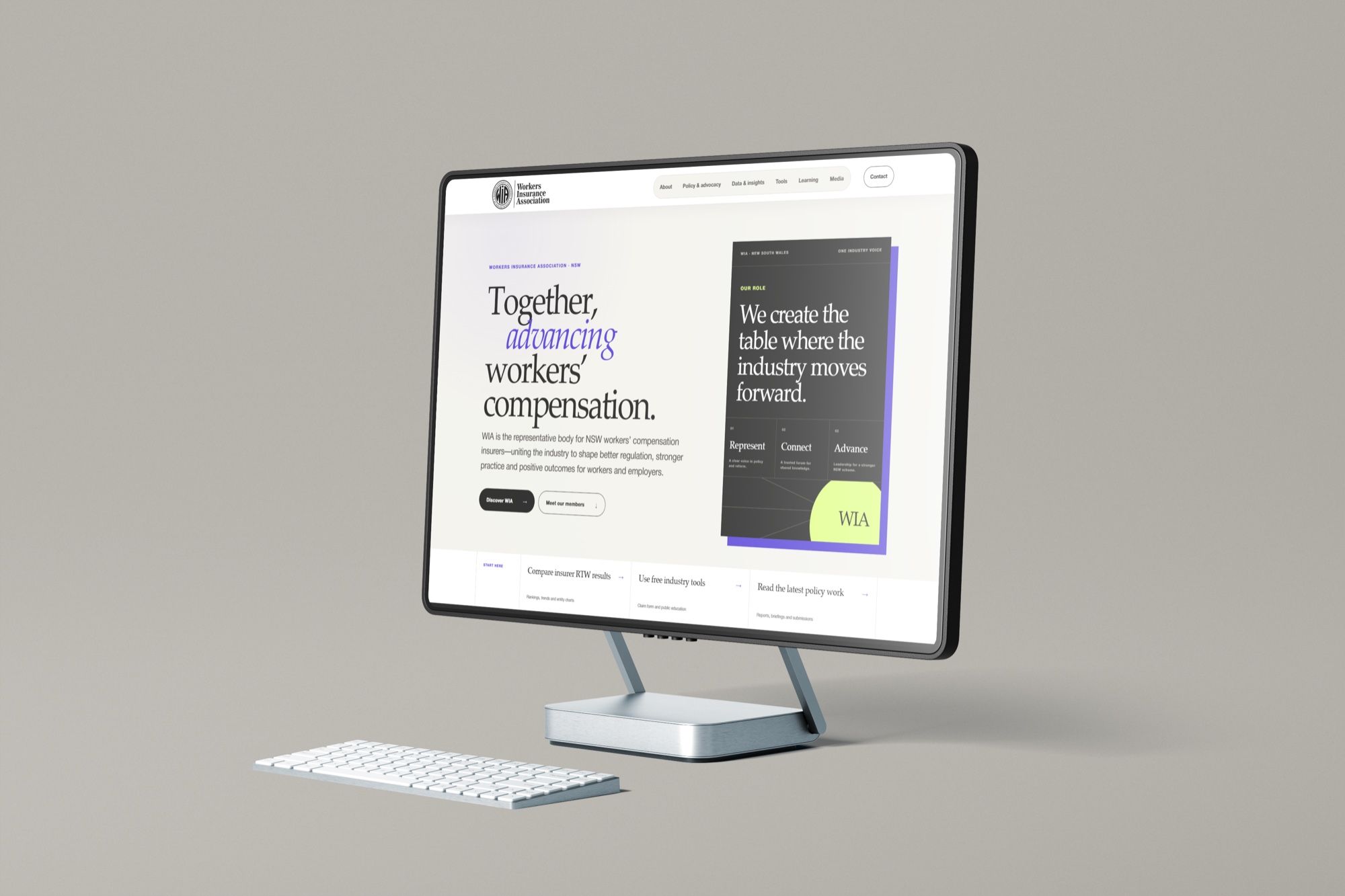 A desktop monitor on a warm grey background showing the association's homepage, headed Together, advancing workers' compensation, beside a dark card.